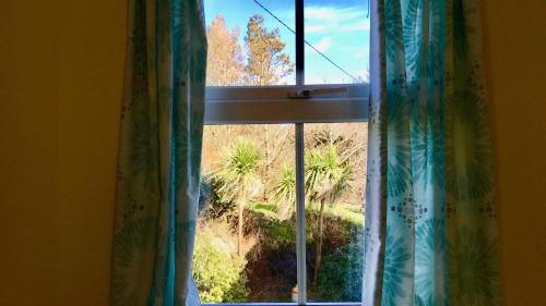 a window with curtains with a view of a field at Carraig-Mor House Bed & Breakfast in Toormore