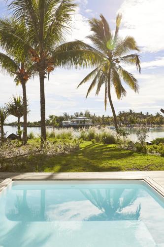 a swimming pool with palm trees in the background at LUX* Grand Gaube Resort & Villas in Grand Gaube