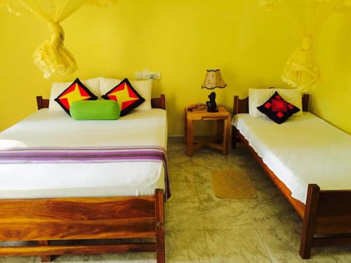 2 camas en una habitación con paredes amarillas en Sigiri Rainbow Lodge, en Sigiriya
