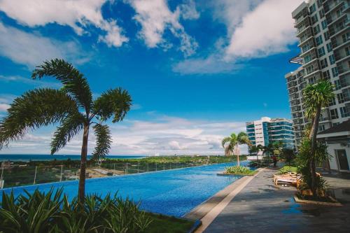 a swimming pool with palm trees and a building at Mactan Newtown Condo in Mactan