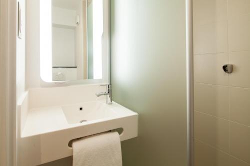 a white bathroom with a sink and a mirror at B&B HOTEL Paris Sud Chatenay Malabry in Châtenay-Malabry