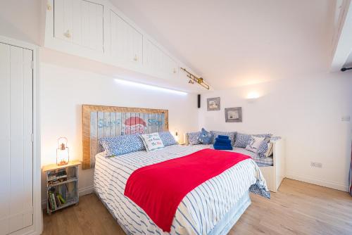 a bedroom with a large bed with a red blanket at Driftwood in Bude