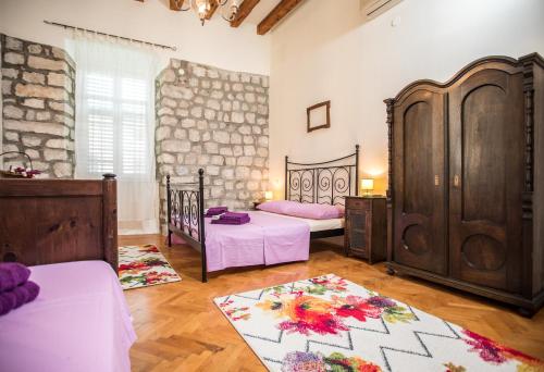 a bedroom with two beds and a stone wall at Old Palace Apartment in Dubrovnik