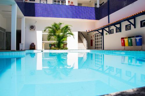 a large swimming pool with a palm tree in the middle at Hotel Diamantina - em Guarapari in Guarapari