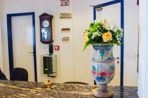 a vase with flowers in it sitting on a table at Hotel Diamantina - em Guarapari in Guarapari