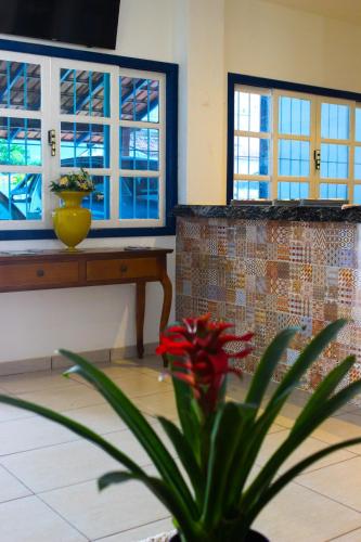 a plant in a room with a table and two windows at Hotel Diamantina - em Guarapari in Guarapari