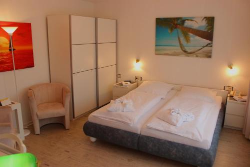 ein Schlafzimmer mit einem Bett und einem Stuhl darin in der Unterkunft Hotel Garni La mer in Bad Zwischenahn