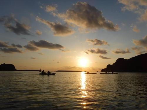 a group of people in boats on the water at sunset at Oli Oli Guesthouse in Shimoda