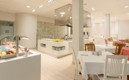 a restaurant with white tables and chairs and a buffet at Apartamentos Santa Rosa in Costa Teguise