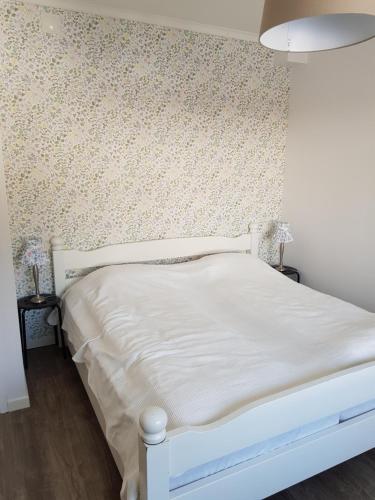 1 dormitorio con cama blanca y papel pintado con motivos florales en Voxnabruks Kanot & Camping, en Voxnabruk