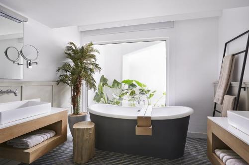 
a bathroom with a tub, sink, and toilet at LUX* Grand Gaube Resort & Villas in Grande Gaube
