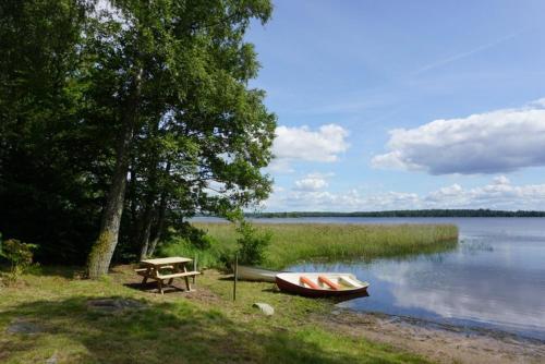 una mesa de picnic y un barco a orillas de un lago en Hunnebo, en Lönashult