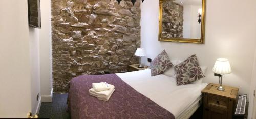 a bedroom with a bed and a stone wall at Royal Mile Suites by the Castle in Edinburgh
