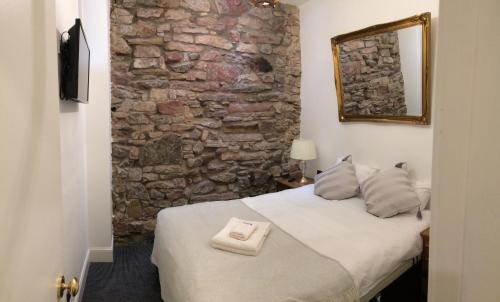 a bedroom with a bed with a stone wall at Royal Mile Suites by the Castle in Edinburgh