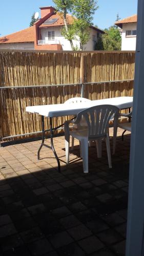 a white table and a bench in front of a fence at Alona in Kefar Weradim