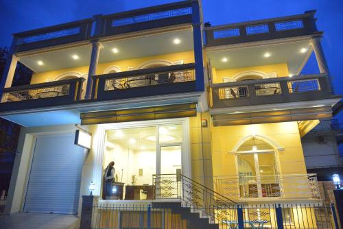 a tall yellow building with a person standing in the doorway at Royal's Studios in Loutra Edipsou