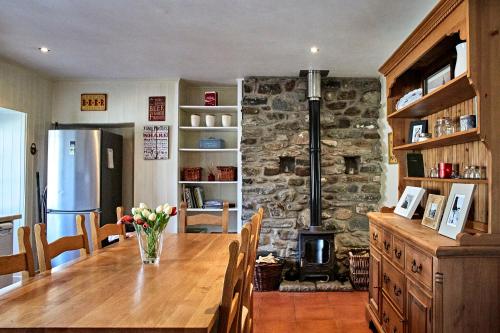 cocina con mesa de madera y chimenea de piedra en Glenalbyn Cottage, en St Fillans