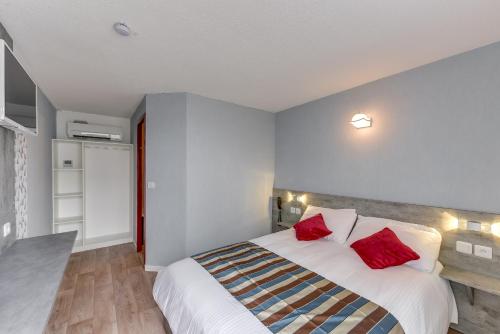 a bedroom with a large bed with red pillows at The Originals Access, Hotel Thouars in Thouars