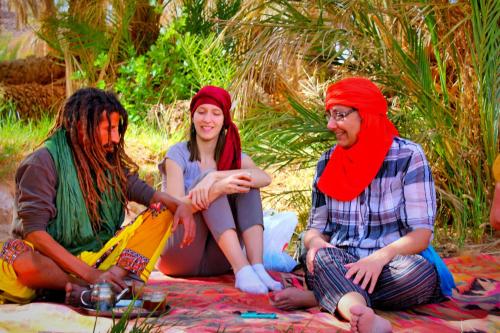 grupa trzech osób siedzących na kocu w obiekcie Dar rawi w mieście Taghit