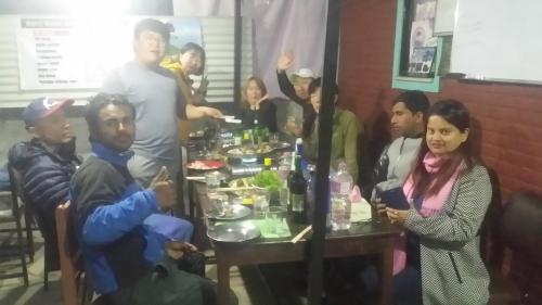 a group of people sitting around a table with food at Harry Guest House & Restaurant in Pokhara
