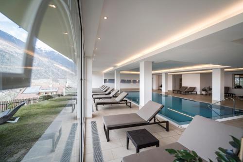 - une piscine et des chaises longues dans un bâtiment dans l'établissement Hotel Erzherzog Johann, à Schenna