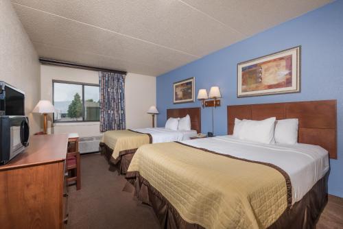 a hotel room with two beds and a flat screen tv at Ramada by Wyndham Fargo in Fargo