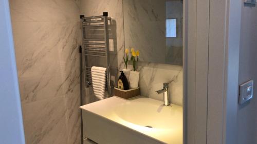 a white bathroom with a sink and a mirror at Different Atmosphere Suite in Caesarea