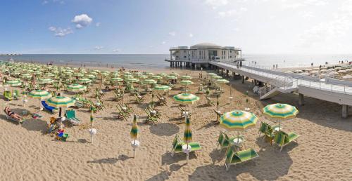 a beach with many chairs and umbrellas and a pier at Appartamento Via Rieti in Senigallia