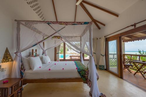a bedroom with a canopy bed with a view of the ocean at Warere Beach in Nungwi