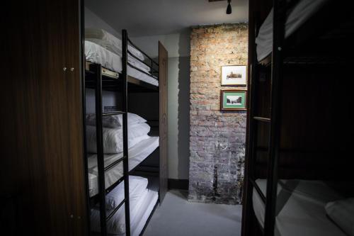 a room with bunk beds and a brick wall at PubLove @ The Crown, Battersea in London