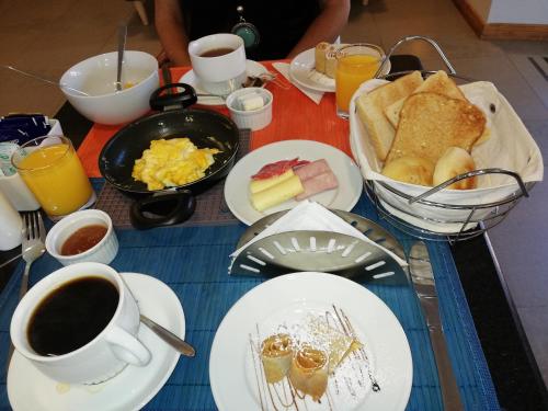 een tafel met borden vol ontbijtproducten en koffie bij Andes Suites in Santiago