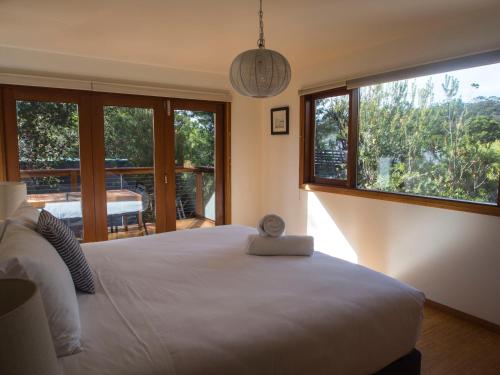 een slaapkamer met een groot wit bed en grote ramen bij Freycinet Studios "Nook" in Coles Bay