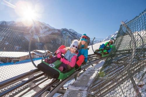 two girls riding on a roller coaster in the snow at Apartment Kaprun in Niedernsill