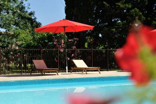 two chairs and a red umbrella next to a pool at Gîtes Domaine des Machottes in Grans