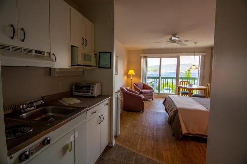 een keuken met een wastafel en een bed in een kamer bij Chalets Condos sur le Fjord in LʼAnse-Saint-Jean