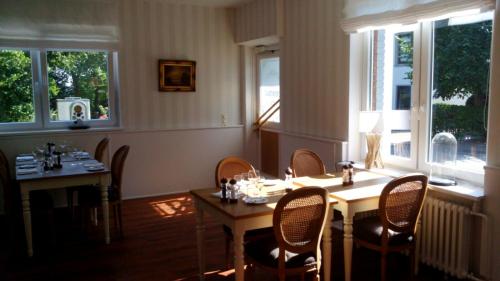 un comedor con mesas, sillas y ventanas en Hotel am Nordkreuz, en Flensburg