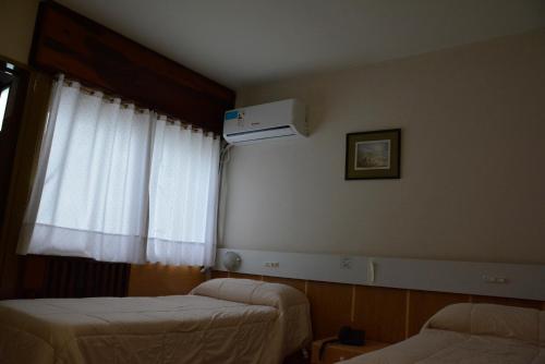 a hotel room with two beds and a window at Hotel Menossi in Río Cuarto