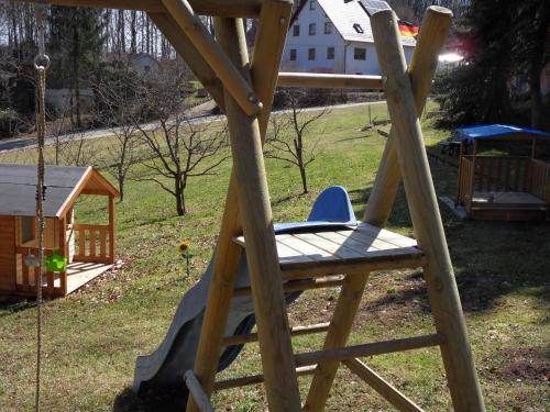 a wooden swing in a yard with a playground at FeWo/GZ Hannelore Müller in Leienfels