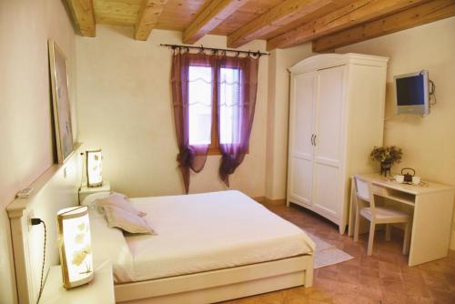 a bedroom with a bed and a desk and a window at Agriturismo Monte degli Aromi in Villaga