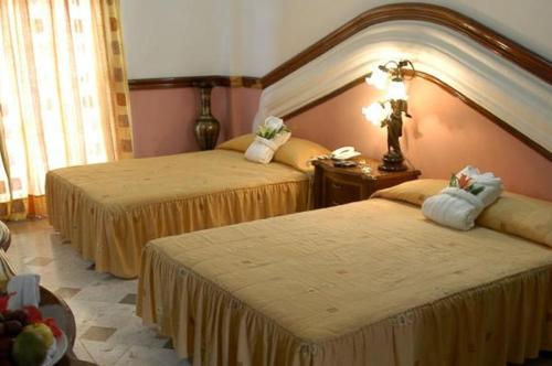 a hotel room with two beds and a table at Canadian Resort Huatulco in Santa Cruz Huatulco