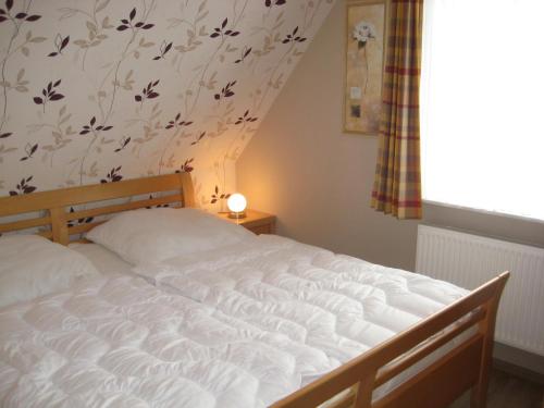 1 cama en un dormitorio con una pared de flores en Ferienhaus Uhlenhorst, en Büsumer Deichhausen
