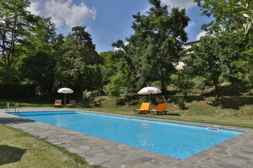 - une piscine avec 2 chaises longues et 2 parasols dans l'établissement Villa Marina, à Terranuova Bracciolini