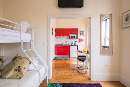a bedroom with a bunk bed and a kitchen with red cabinets at À Francos Burguer Station in Porto