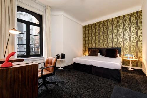 a hotel room with a bed and a desk and a chair at Vintage Hotel Brussels in Brussels