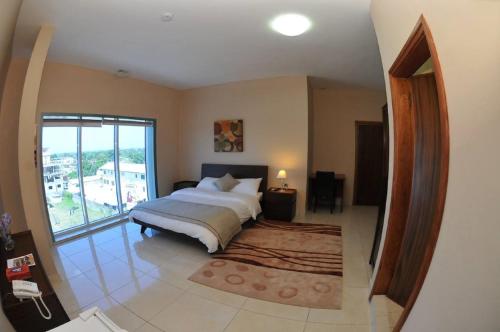 a bedroom with a large bed and a large window at Murex Plaza Hotel & Suites in Monrovia