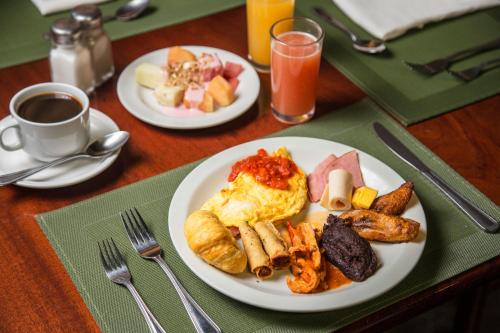 two plates of breakfast food on a table with coffee at Conquistador Hotel & Conference Center in Guatemala