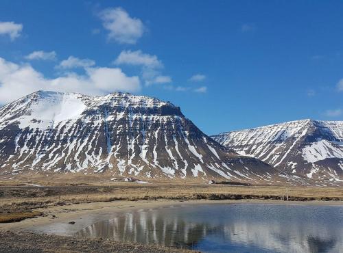 a snow covered mountain with a lake in front of it at Holt Inn in Flateyri