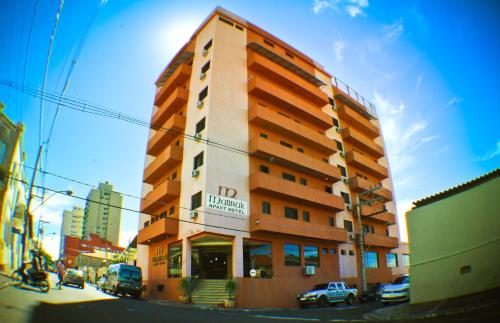 a building on a street with cars parked in front of it at Mabruk Barretos Apart Hotel in Barretos