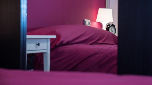 Cama con almohadas moradas y mesa con lámpara en Apartamento Deluxe, en Zamora