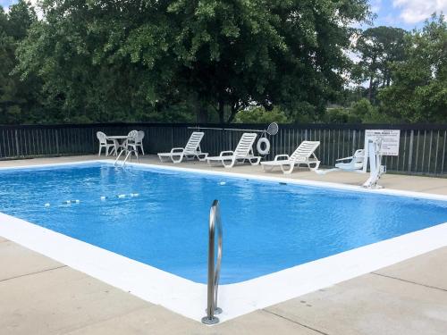 a swimming pool with chairs and a table and chairs at Econo Lodge in Metter